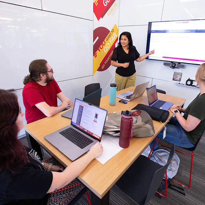 Four people in a group study room interacting