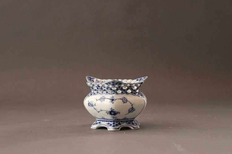 White sugar bowl with wide paneled body featuring blue decorations in various patterns with central delicate floral motif and outward flaring lip with laced-like pierced work.