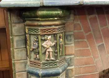 Left column under mantel, green glaze on top, three figures in panels