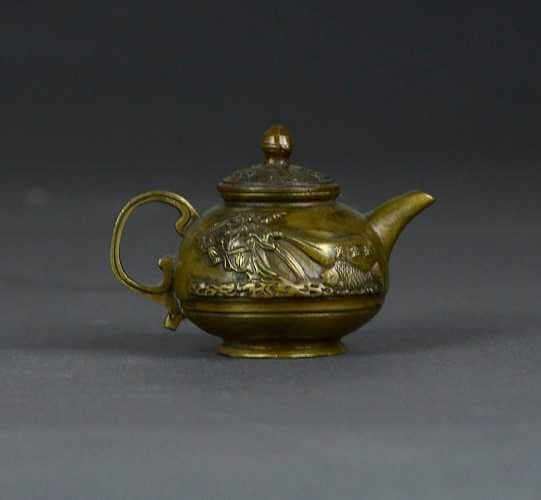 Small marsh colored teapot with a rounded body featuring relief molded decoration of Buddha and carp with Chinese characters.
