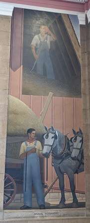 Tall mural showing twol light-skinned men in overalls by a barn. 1 is on the upper level of the barn, wiping sweat from his forehead. 1 is holding two white horses.