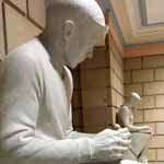 Sculpture of a boy in the foreground with the sculpture of a girl in the background.