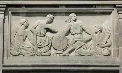 The bas-relief depicts four men seated around a globe. The first man holds a gear while the second man looks intently at the globe. The third man holds a Caduceus while looking away from the globe and the fourth man leans against a cushion while holding a sheaf of grain.