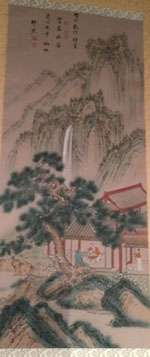 Long scroll with Chinese text at the top showing dark green trees in the center above a red house with people in it and a waterfall above