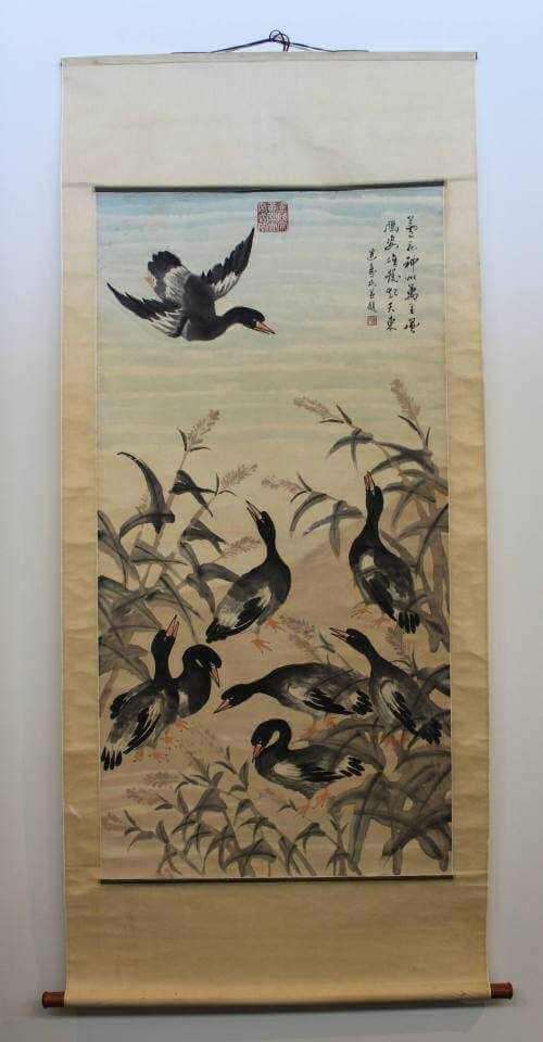 Hanging scroll showing multiple ducks in a pond with vegetation, one duck in flight above and a three columned calligraphy inscription on the top right.