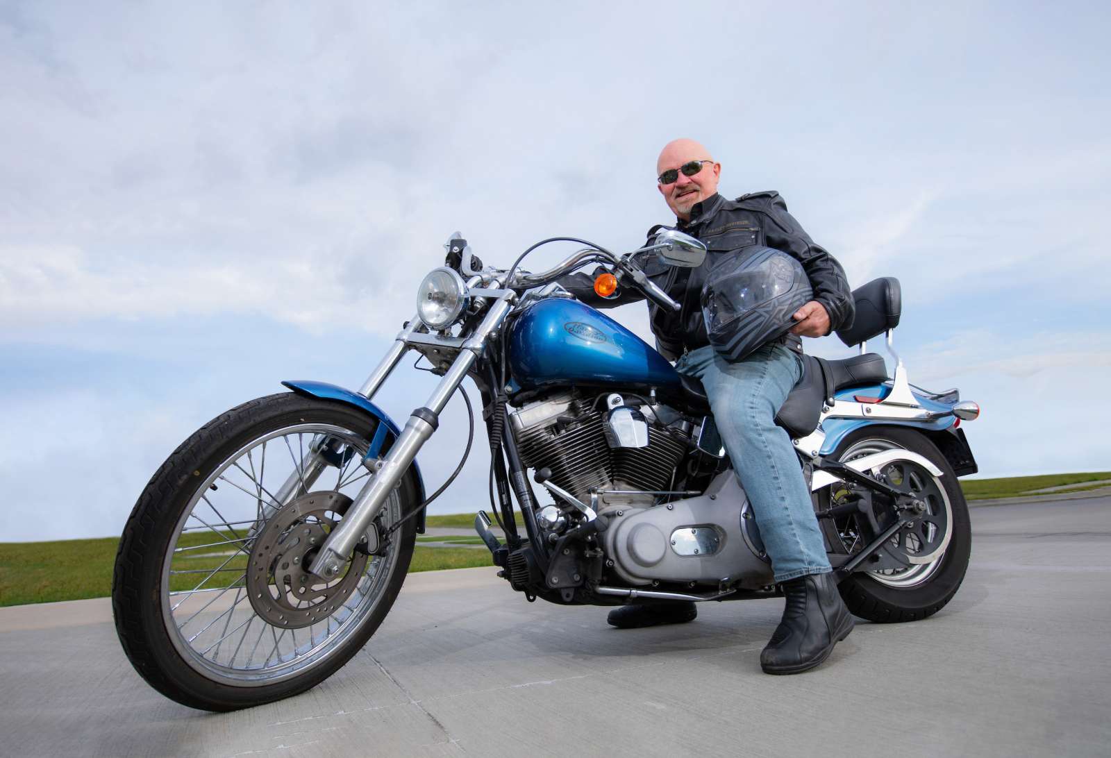 Man sits on a Harley-Davidson motorcycle holding a helmet